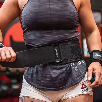 Female crossfit athlete securing Murgs 5'' weightlifting belt with self locking buckle and hook and loop