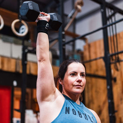 Female athlete dumbell pressing with Murgs cotton wrist wraps in black